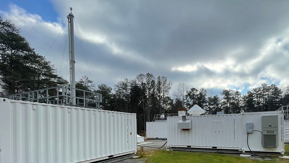 The Bankhead National Forest Aerosol Observing System (left) and Ka-Band ARM Zenith Radar (on the roof of the instrument container to the right) are shown on a cloudy day. The forest is visible above and between the instrument containers.