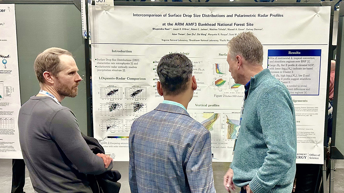 Three people are standing with one another in front of a poster pinned to a board. The poster is titled, "Intercomparison of Surface Drop Size Distributions and Polarimetric Radar Profiles at the ARM AMF3 Bankhead National Forest Site."