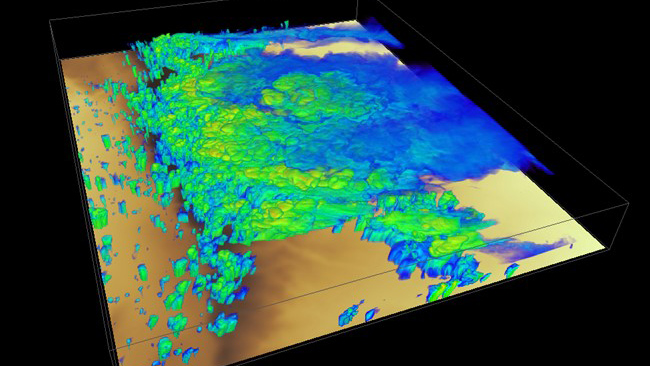 A rendering of simulated radar reflectivity displays varying shades of blue, green, and yellow against a surface made up of different shades of brown. The brown shades indicate the terrain height, with darker shades being higher terrain. The blue, green, and yellow colors represent the reflectivity, with warmer colors indicating higher reflectivity.