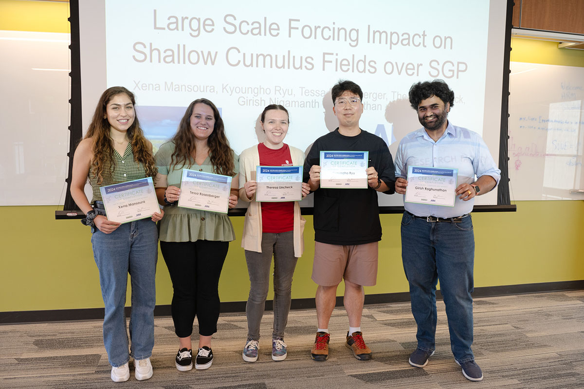 Five people hold certificates while standing in front of a slide that says,