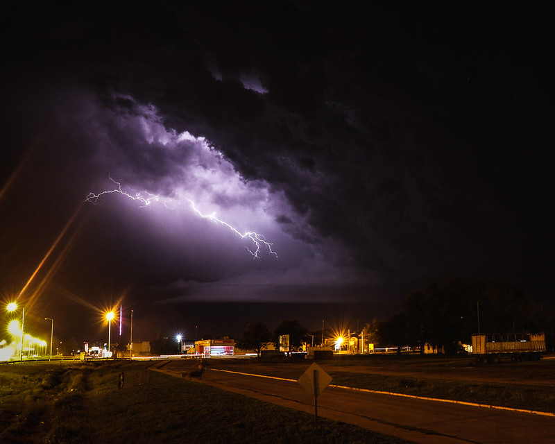 A lightning bolt brightens the nighttime sky over a town.