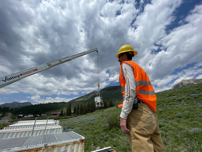 Wearing an orange safety vest and yellow hard hat, John Bilberry watches a crane move an instrument into place.