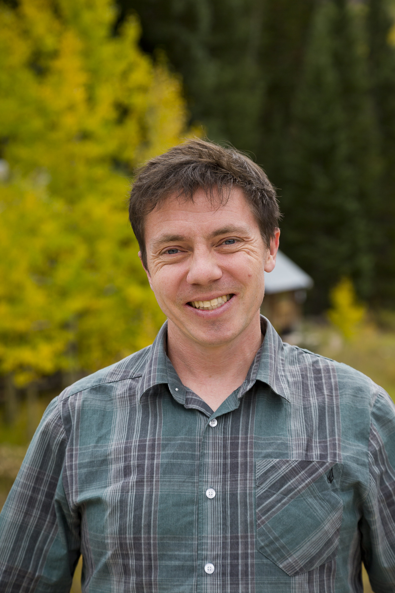 In front of yellow-green leaves, Daniel Feldman smiles for the camera. 