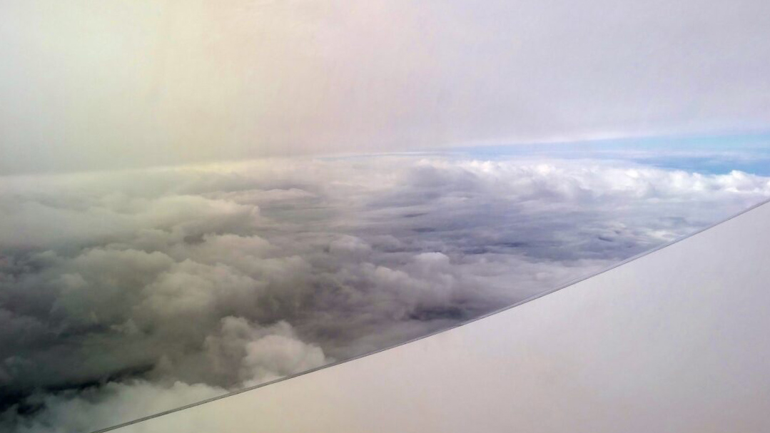 A photo captures fluffy clouds below an aircraft window.