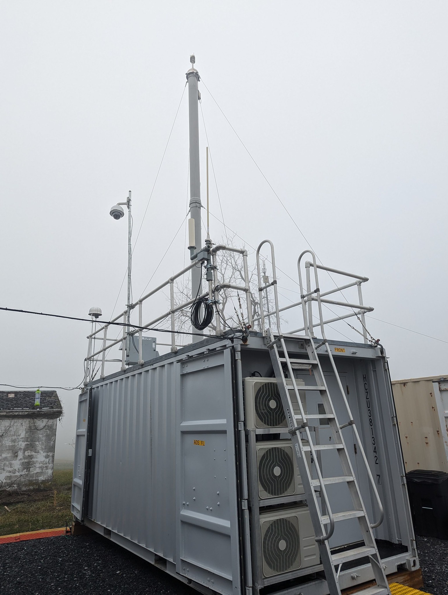 A shipping container with an aerosol stack sticking up from the roof