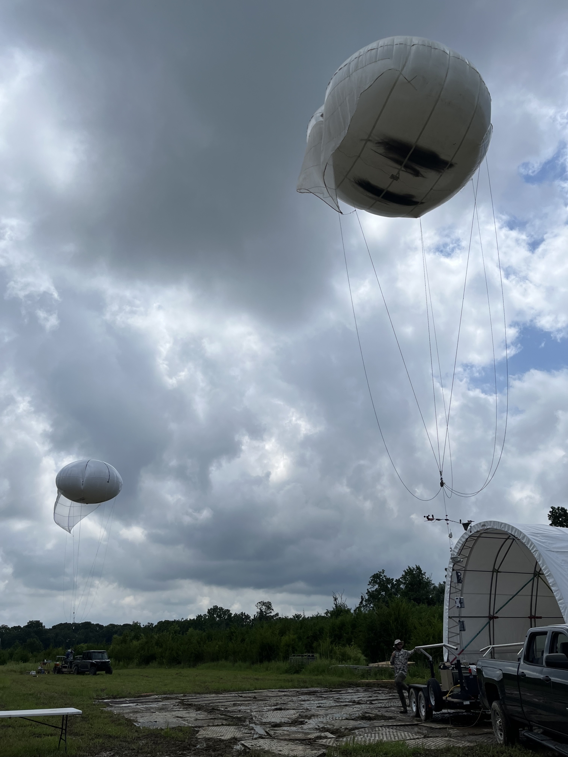 Two tethered balloon systems operate near each other on a cloudy day.