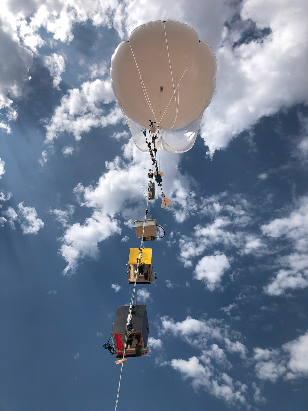 A tethered balloon carries instruments aloft under a cloud-filled sky.