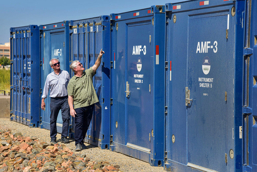 Fred Helsel points up at the top of an AMF3 shelter as Mark Ivey observes behind him.