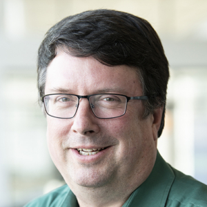 Wearing a jade green collared shirt, Mike Jensen smiles at the camera.