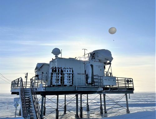 A weather balloon is launched from an instrument platform surrounded by snow
