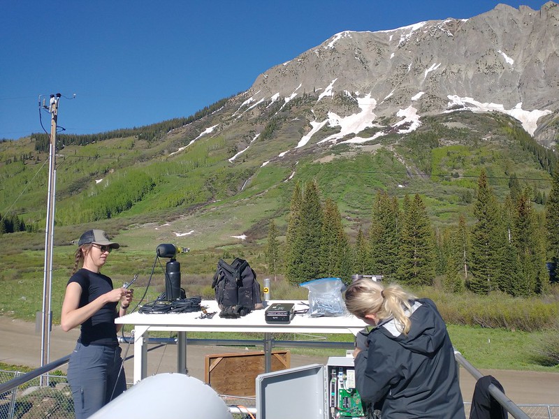 Two technicians work on the roof of an ARM Mobile Facility container.