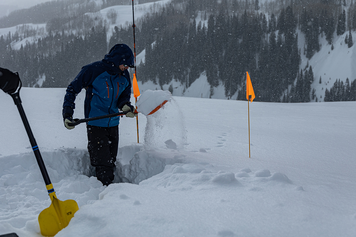 Eli Schwat holds a shovelful of snow from a pit he is digging.